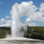 A geyser erupting and spraying a mist of water 
                        straight up into the air