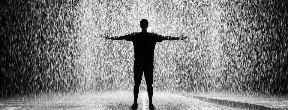 Man standing in the pouring rain with his arms
            stretched out to catch the rain