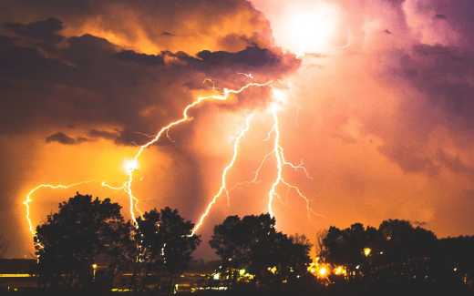 Image of lightning striking alongside the sun in a red sky